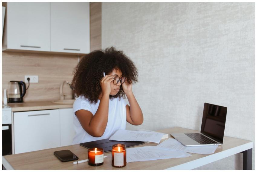 A woman with curly hair works from home on her lap