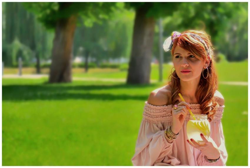 A stylish woman enjoys lemonade in a sunny park se