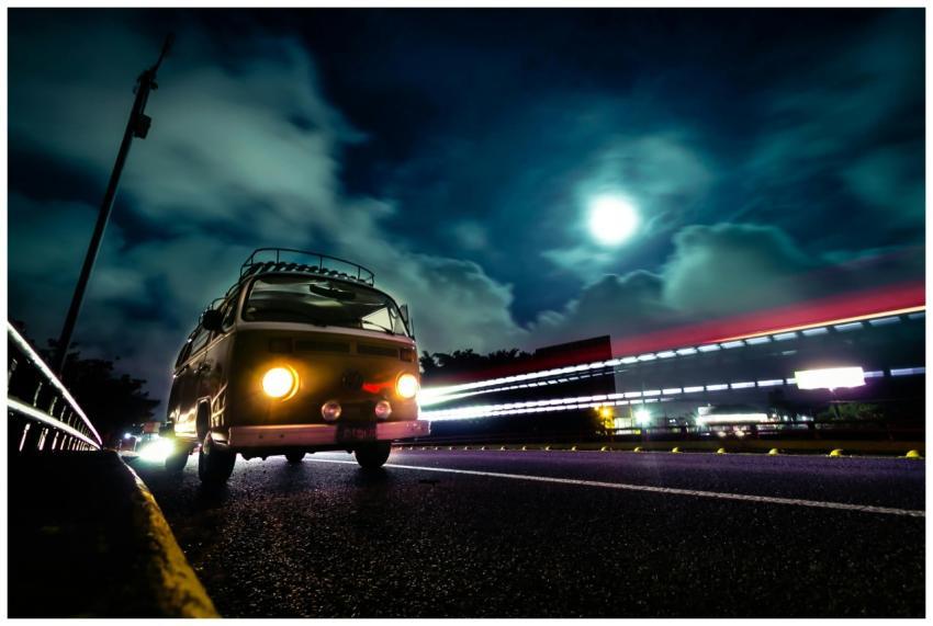 A vintage VW van on a night highway with dramatic