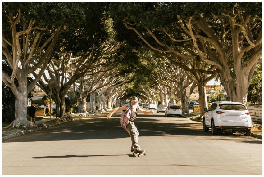An elderly man skateboarding on a sunny day along
