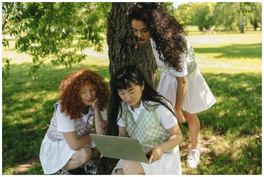 Three diverse students in uniforms studying on a l