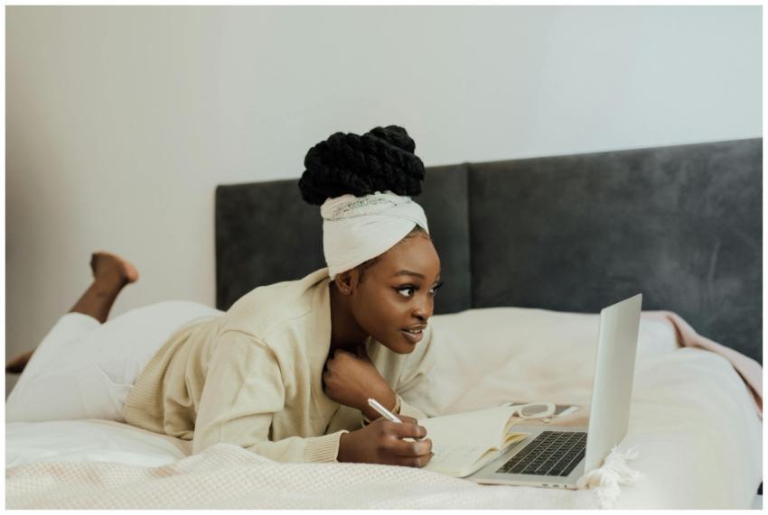 Young woman in headwrap working remotely with lapt