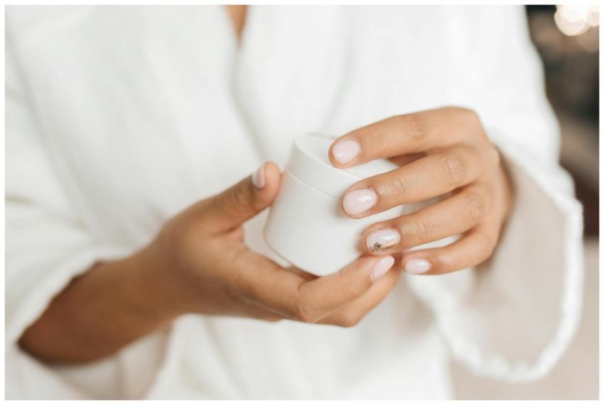 Hands with manicured nails holding a skincare cont