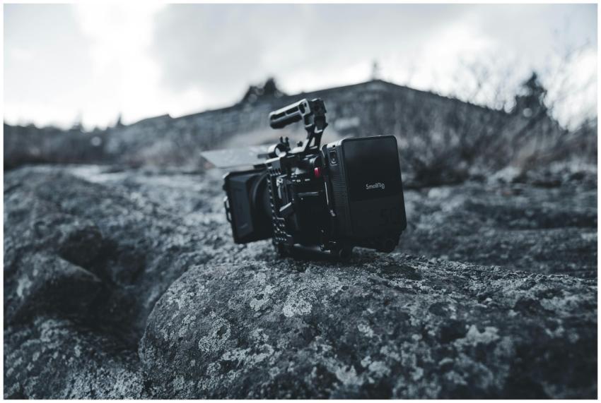 A professional video camera sits on rugged rocks o