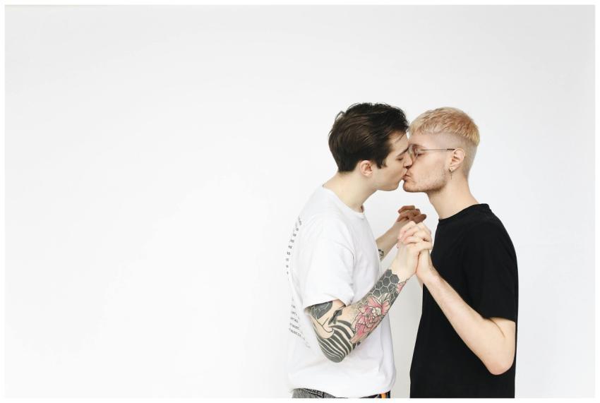 Young gay couple kissing passionately on a white b