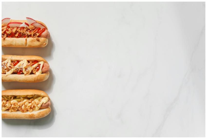 Three gourmet hot dogs with various toppings on a