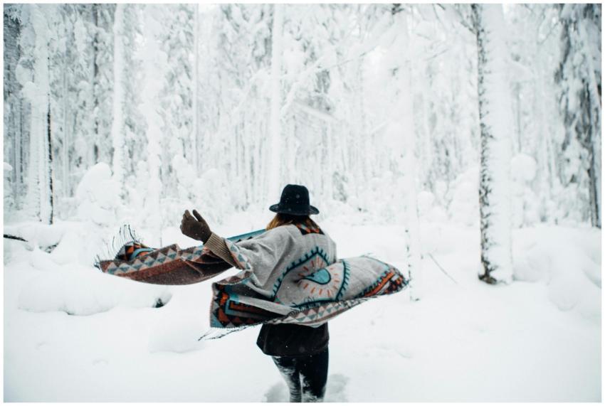 Woman wrapped in a poncho running through a snowy