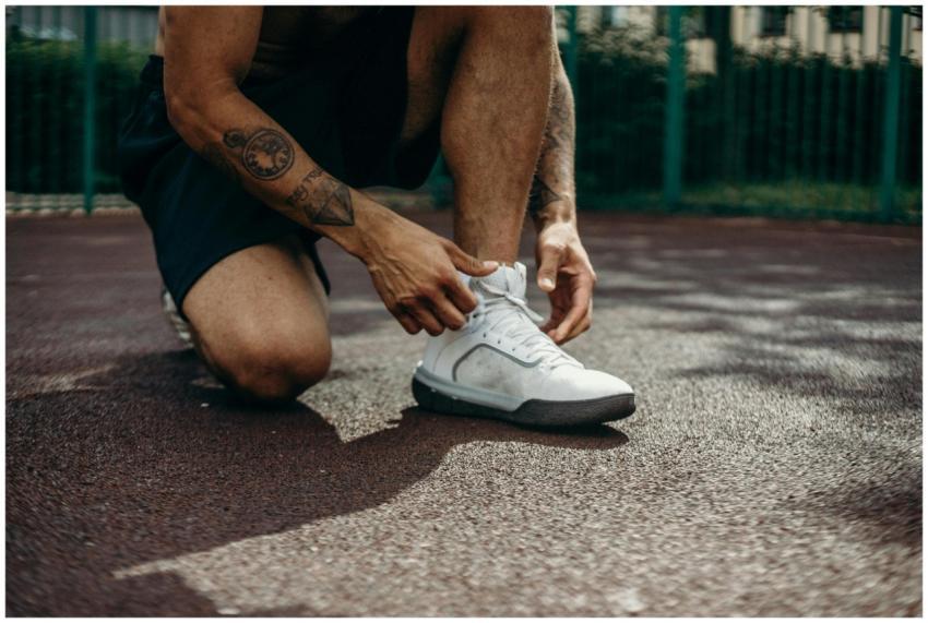 Close-up of a person kneeling and tying white snea