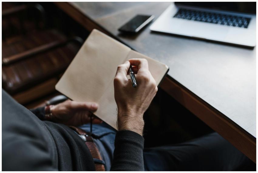 Close-up of a person writing in a notebook at a wo