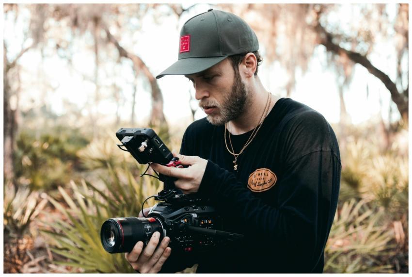 Bearded filmmaker adjusting digital camera equipme