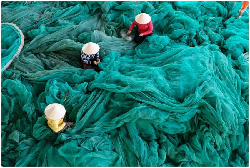 Aerial view of three people weaving turquoise fish