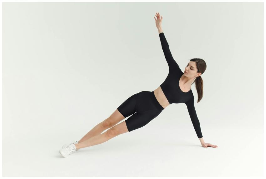 Woman performing a side plank exercise indoors, sh
