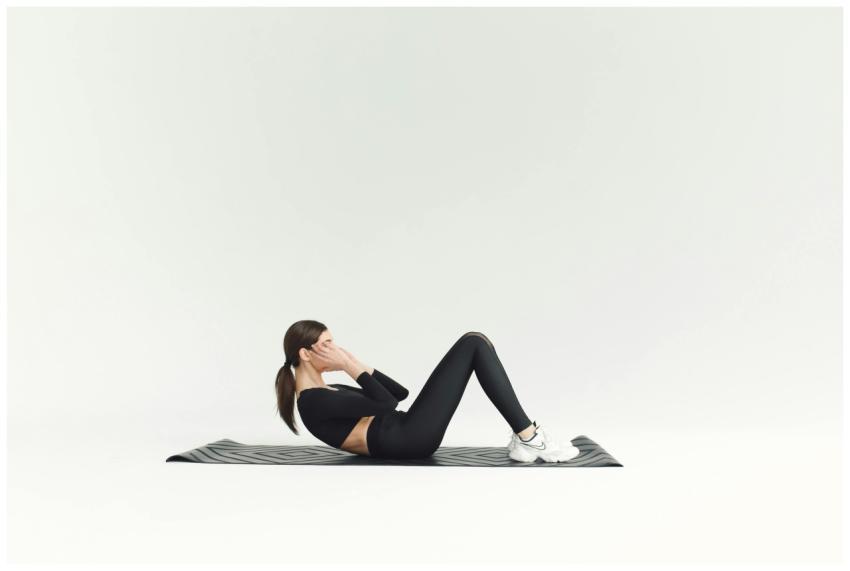Woman in activewear doing sit-ups on yoga mat in b