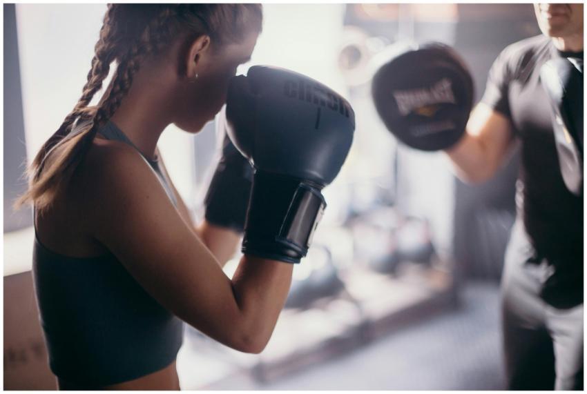 A female boxer and her coach practicing punching t