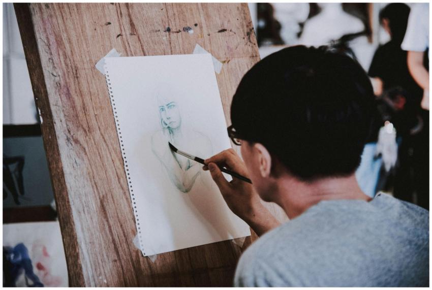 Artist sketching a portrait with a pencil on a woo