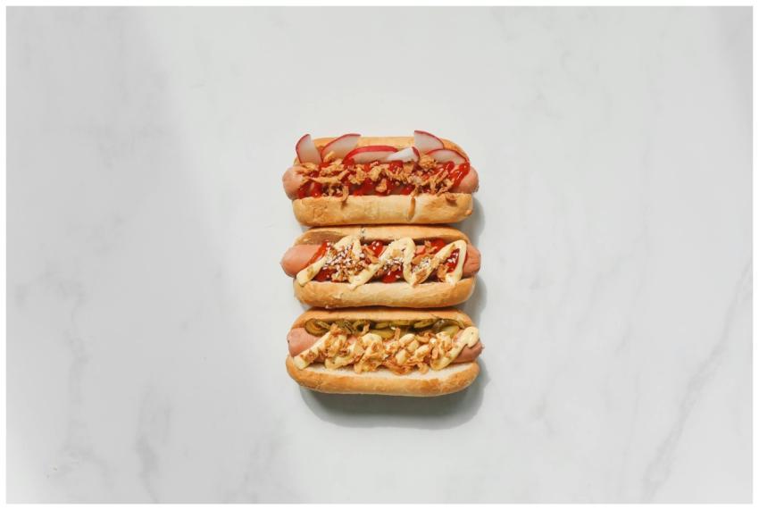 Three gourmet hot dogs with various toppings on a