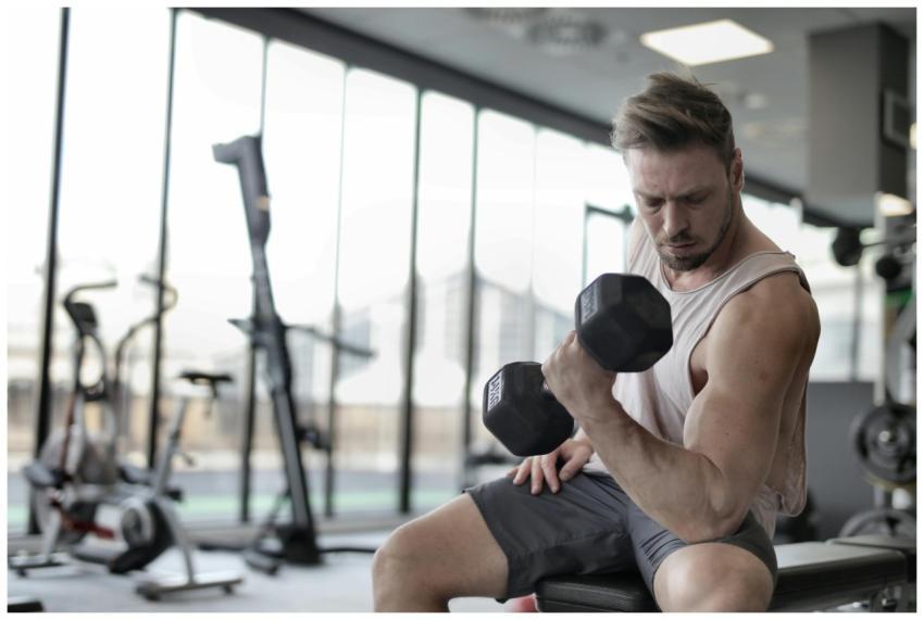 Focused man working out with a dumbbell in a well-