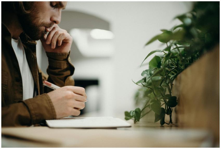 A man deeply concentrates while writing in an indo