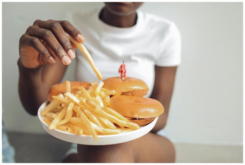 Person enjoying a plate of burgers and fries insid