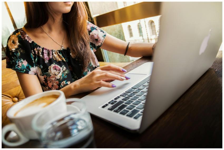 A woman working on a laptop in a cafe, sipping cof