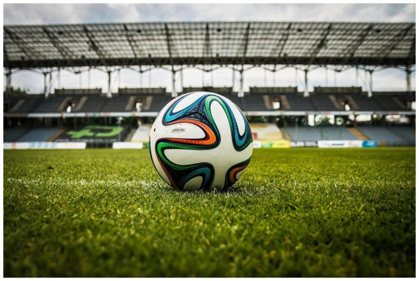 A vibrant soccer ball rests on a lush green field