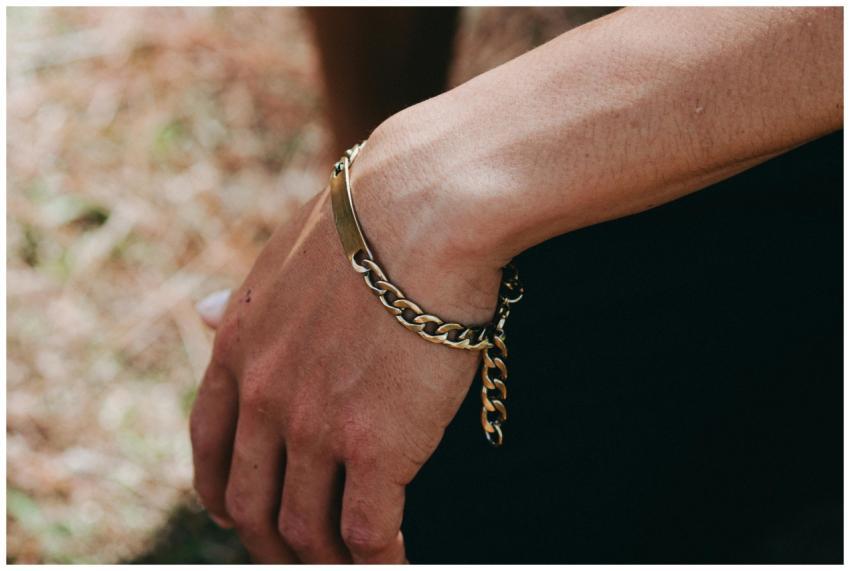 Detailed view of a hand wearing a gold chain brace