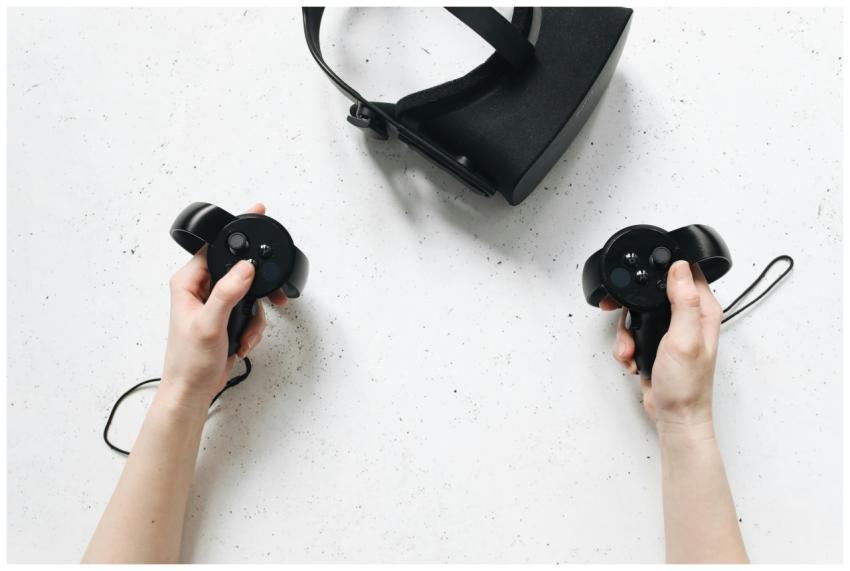 Two hands hold virtual reality controllers above a