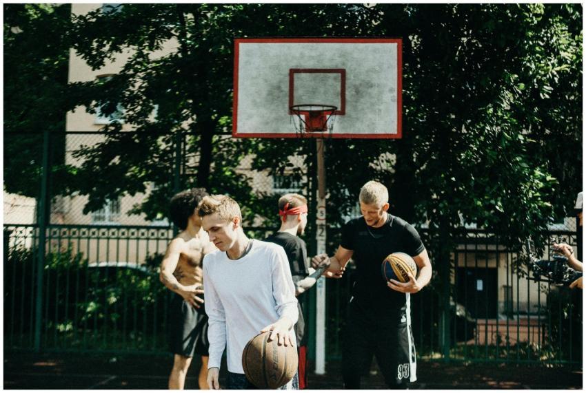 Group of adults playing basketball on an outdoor c