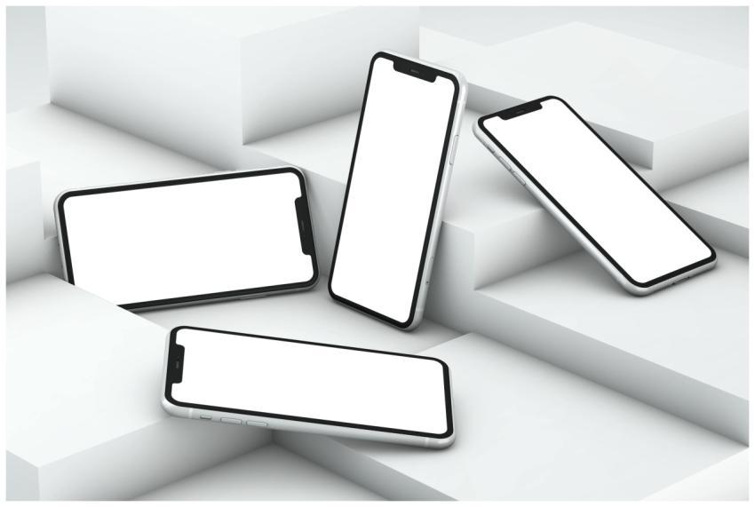 Four smartphones with white screens arranged on ge