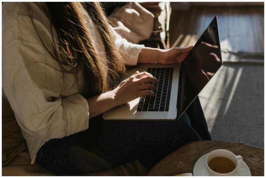 Close-up of a woman using a laptop in a warm, cozy