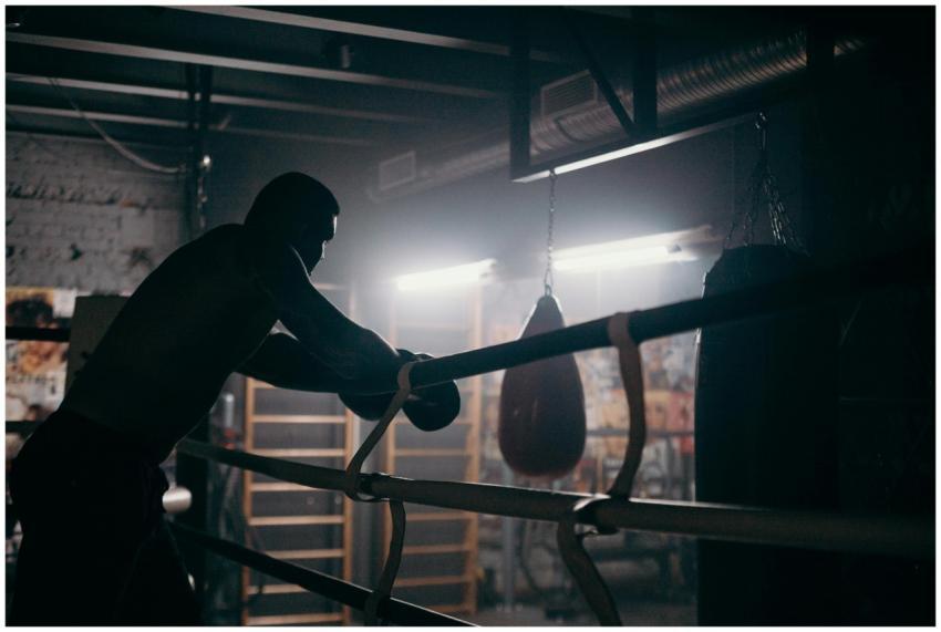 Moody silhouette of a boxer leaning in a dimly lit