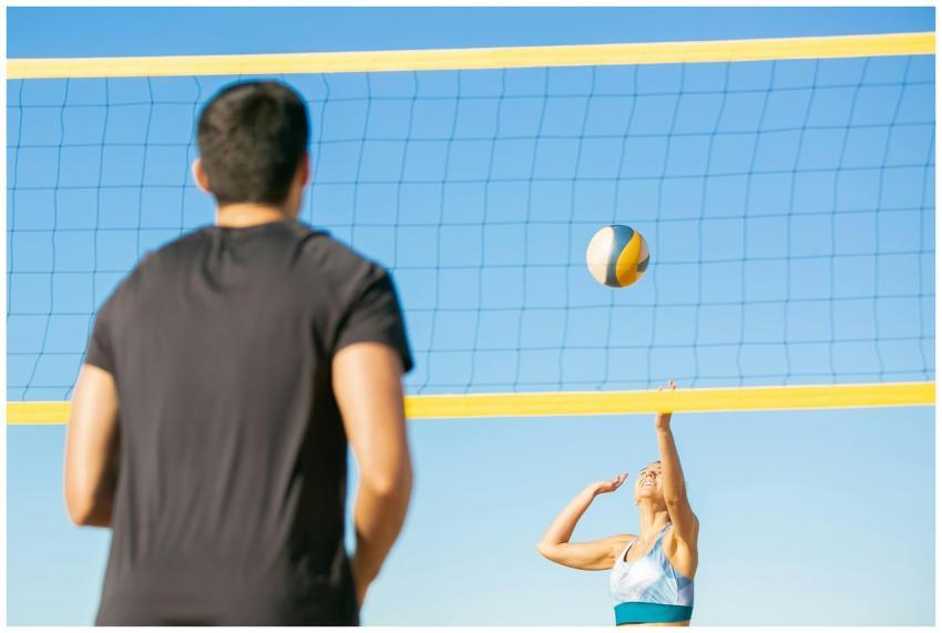 A man and woman playing volleyball on the beach un