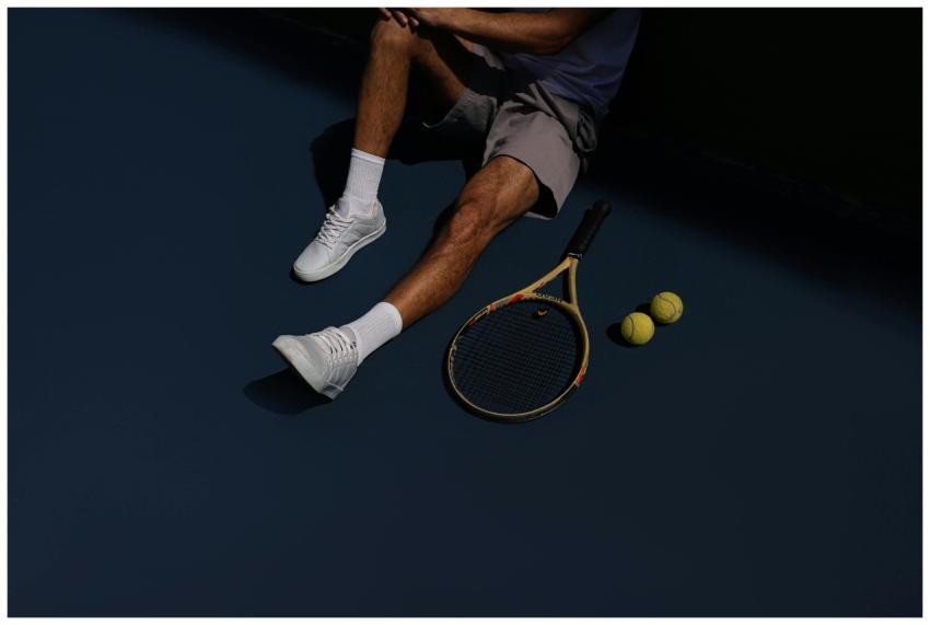A tennis player resting on the court with racket a