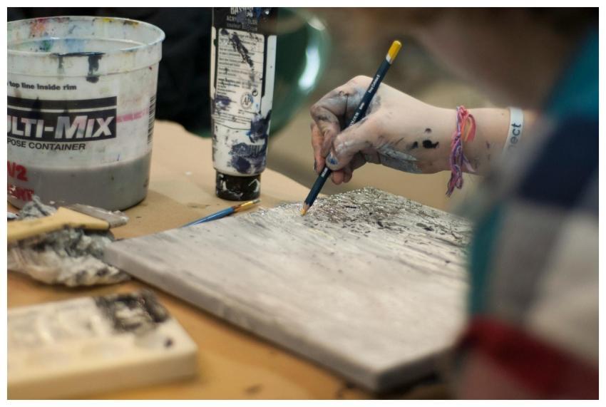 Close-up of an artist's hand painting a textured a