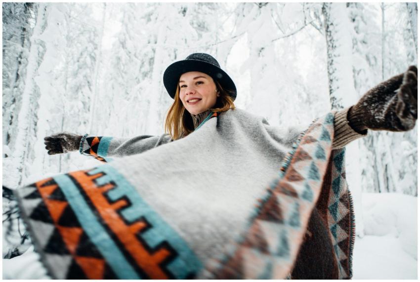 A cheerful woman wearing a geometric poncho and ha
