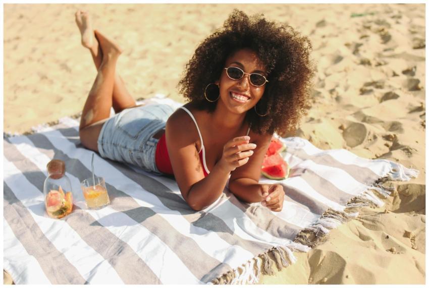 A cheerful woman on a beach towel, enjoying a sunn