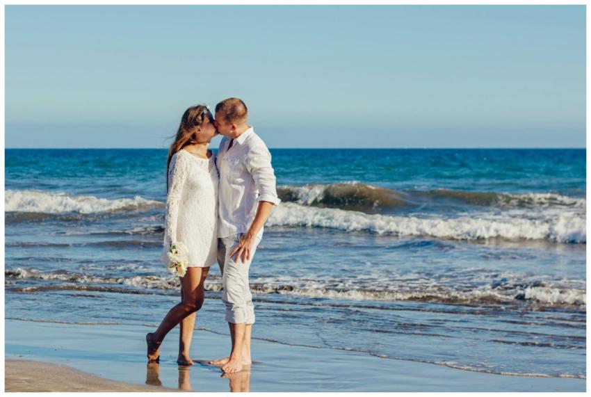 A couple enjoys a romantic kiss on a sunny beach,