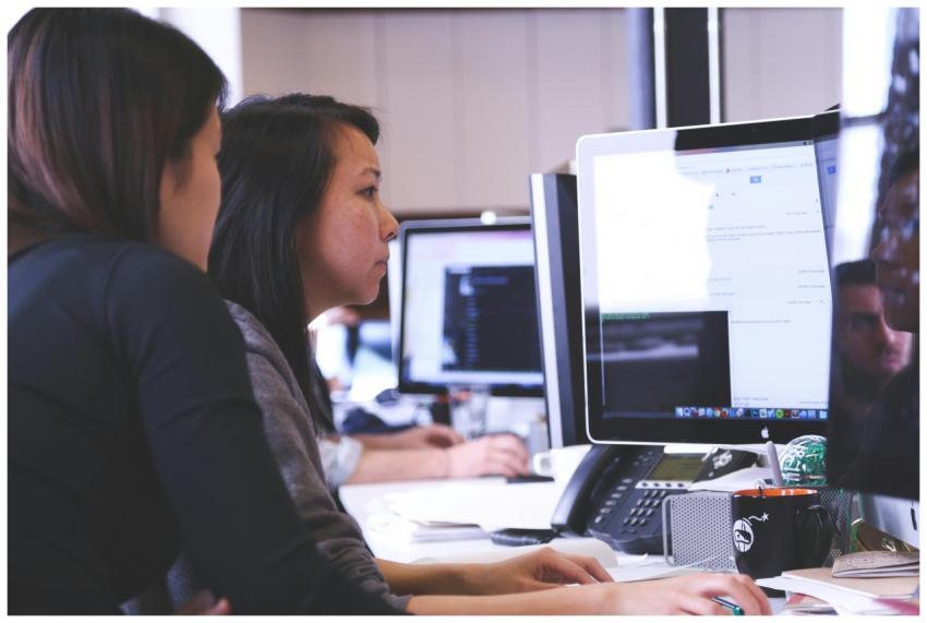 Two women working together on code at a computer i