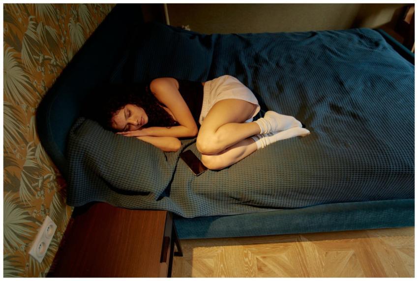A young woman lying on a bed in a bedroom, depicti