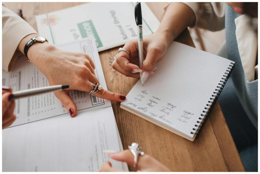 Close-up of hands writing in a notebook while stud