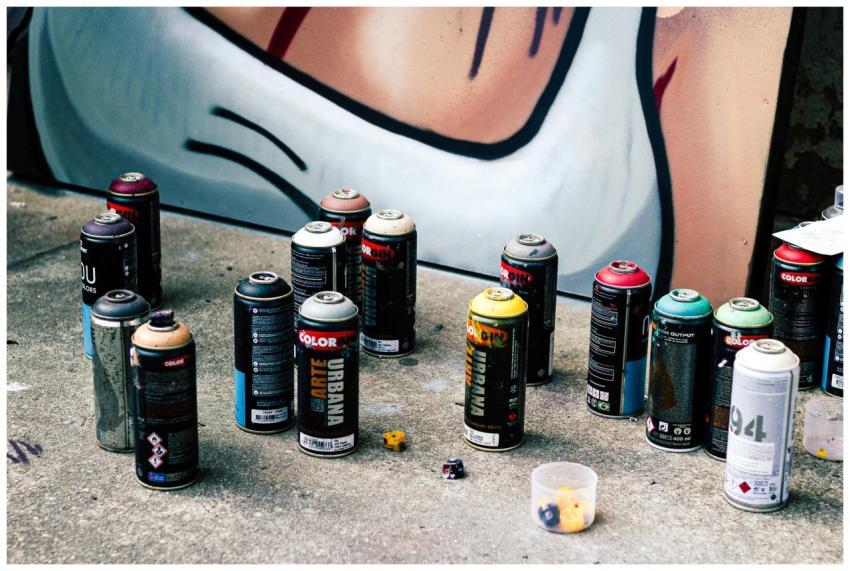 Colorful spray paint cans on concrete in front of