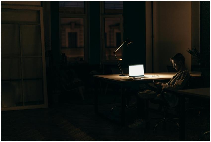 A man working late at night in a dimly lit office,