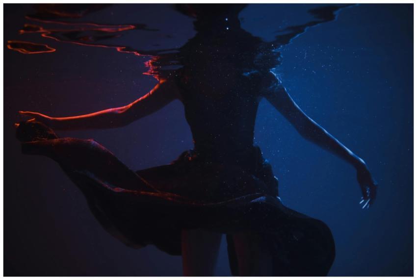 Silhouette of a woman submerged underwater in dram