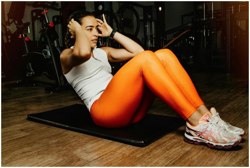 Focused woman doing sit ups in a gym, showcasing f