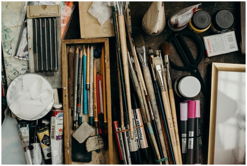 Top view of various art supplies on a desk, showca