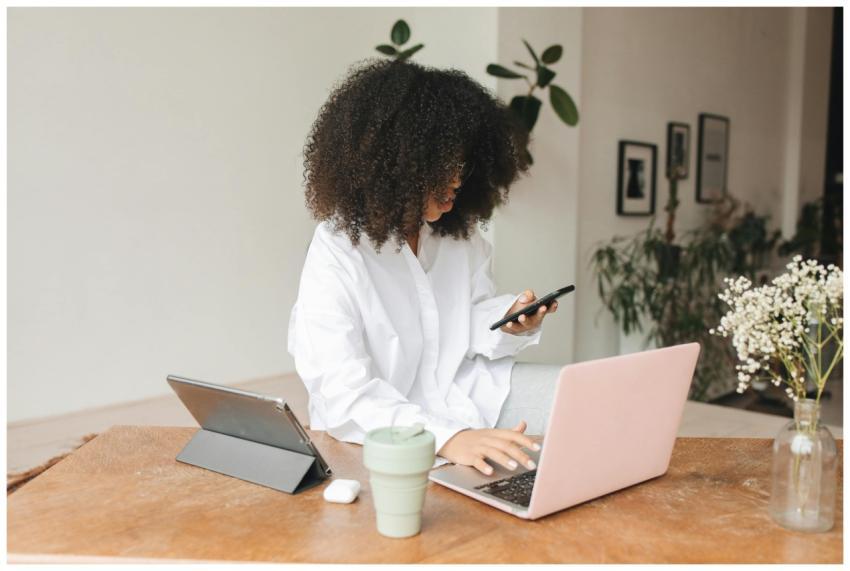 Young woman multitasking at home using laptop, tab