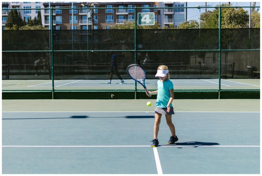 A young girl practicing tennis on an outdoor court