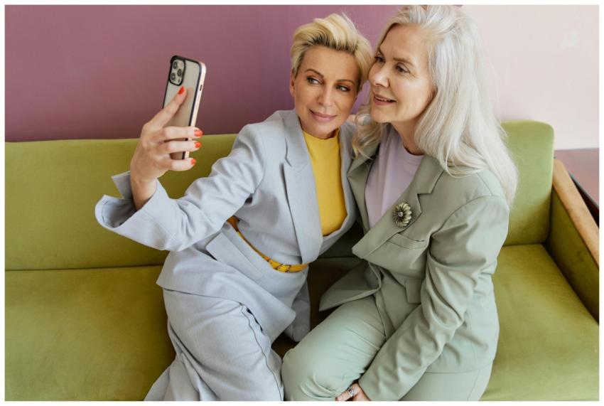 Two stylish women sitting on a couch, capturing a