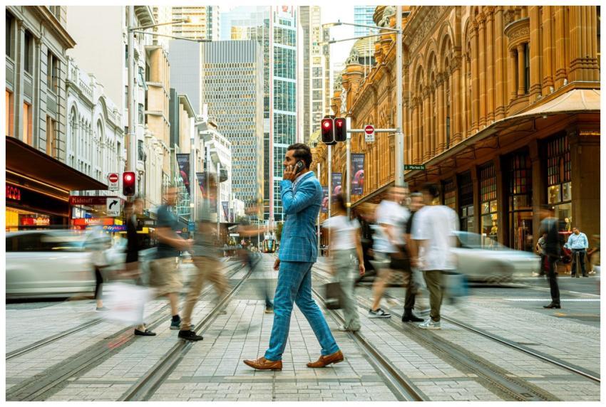 A businessman in a blue suit crosses a busy street