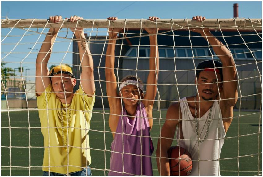 Three diverse young men pose confidently on a socc